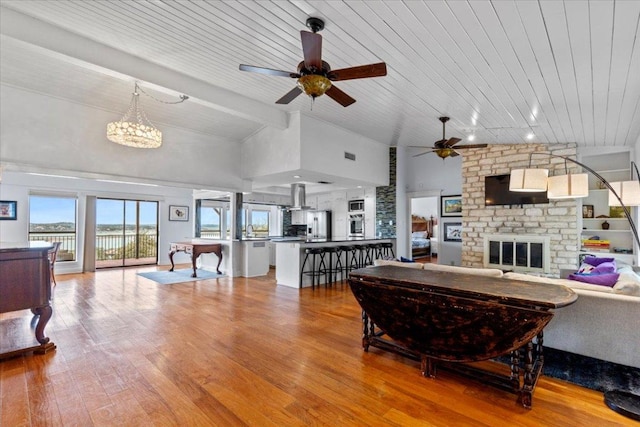 living room featuring visible vents, a brick fireplace, ceiling fan, high vaulted ceiling, and hardwood / wood-style flooring