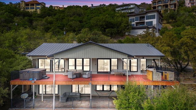 back of property at dusk featuring a deck, metal roof, and a patio