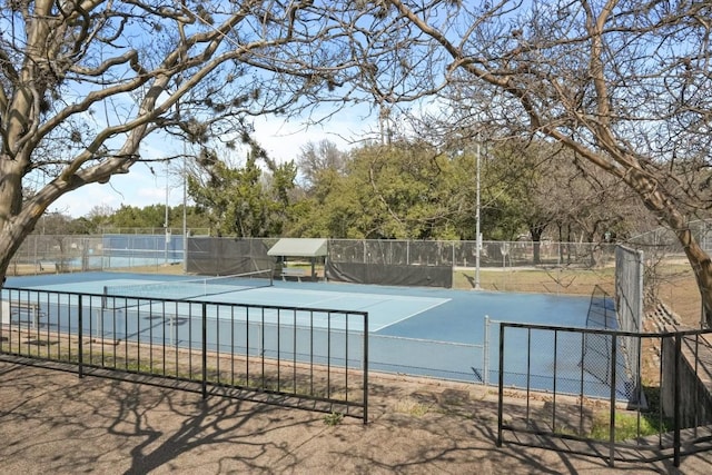 view of swimming pool with a tennis court and fence