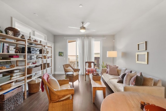 living area with a ceiling fan, wood-type flooring, and baseboards