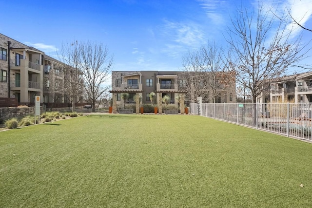 view of property's community featuring fence and a lawn