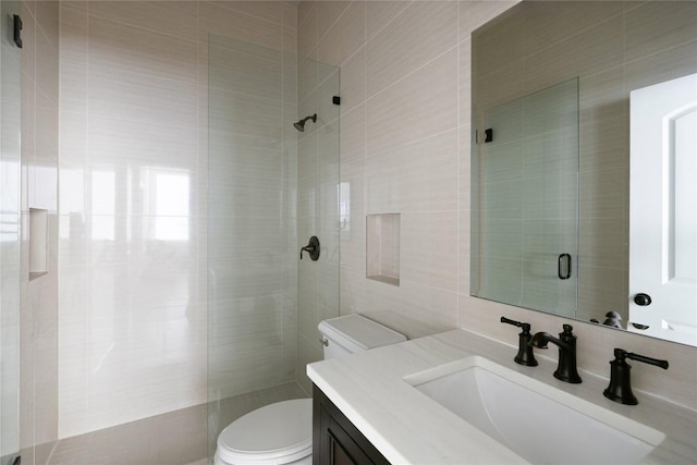 full bath with toilet, a tile shower, tile walls, and vanity