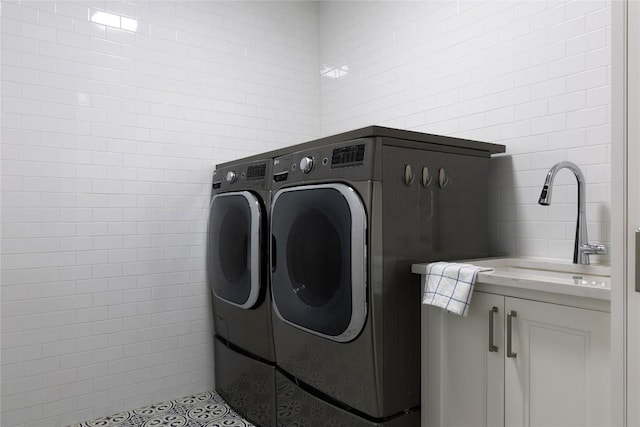 laundry room with cabinet space, washing machine and dryer, and a sink