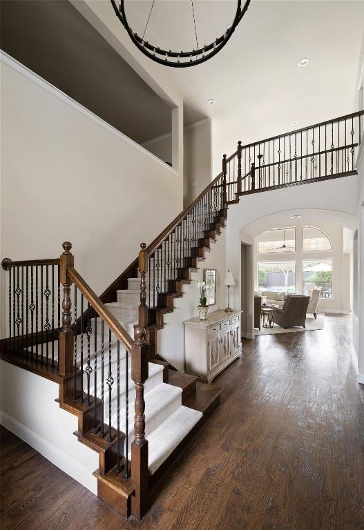 stairway featuring a high ceiling, baseboards, and wood finished floors