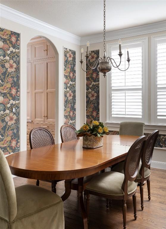 dining room featuring light wood finished floors, arched walkways, and ornamental molding