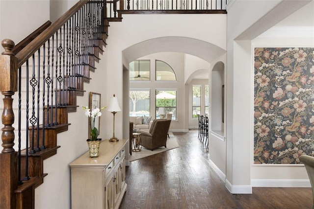 foyer entrance featuring a towering ceiling, baseboards, and dark wood-style flooring