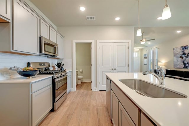 kitchen with visible vents, hanging light fixtures, stainless steel appliances, light countertops, and a sink