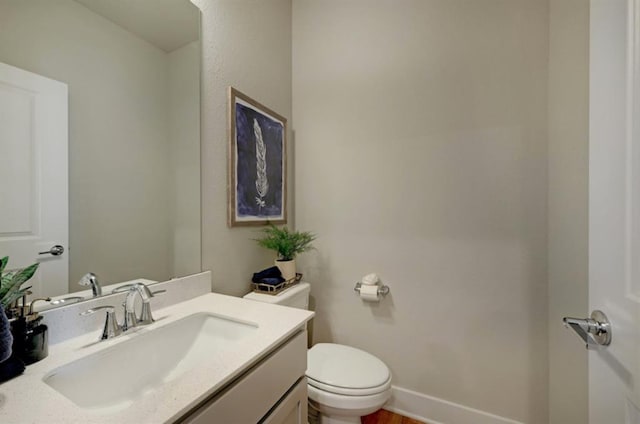 bathroom featuring baseboards, vanity, and toilet