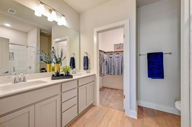 full bath featuring wood finished floors, a stall shower, a sink, and visible vents