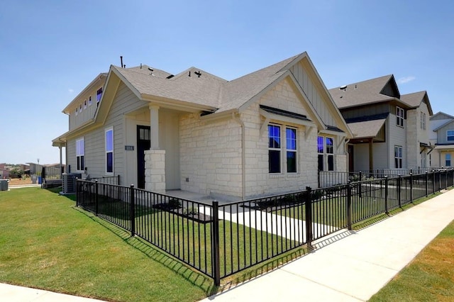 view of front of home with a shingled roof, stone siding, fence private yard, board and batten siding, and a front yard