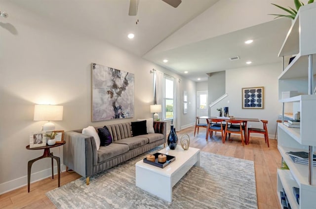 living room with light wood-style flooring, visible vents, vaulted ceiling, and recessed lighting