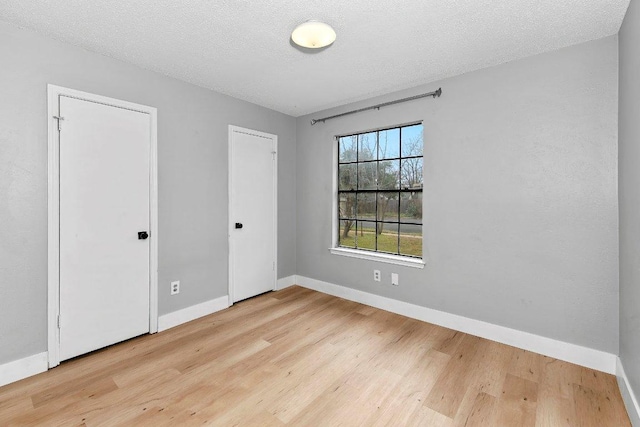 unfurnished bedroom featuring wood finished floors, baseboards, and a textured ceiling