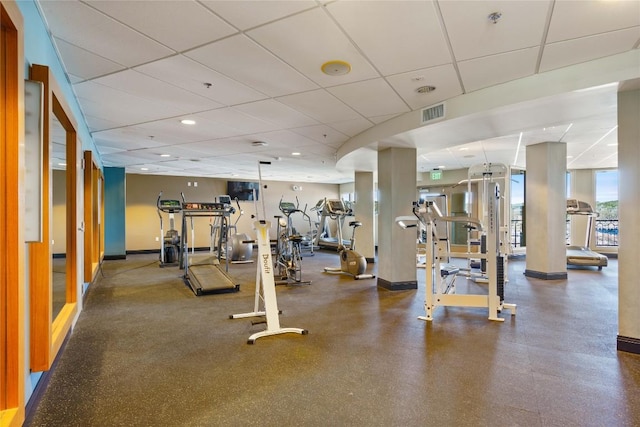 exercise room with baseboards, visible vents, and a drop ceiling