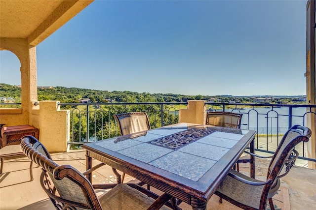 balcony featuring a water view and outdoor dining area
