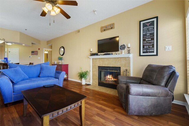 living area featuring wood finished floors, visible vents, ceiling fan, baseboards, and a tile fireplace