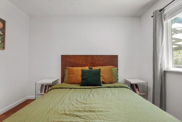 bedroom with multiple windows, baseboards, and wood finished floors