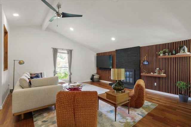 living area with vaulted ceiling with beams, ceiling fan, a fireplace, wood finished floors, and baseboards