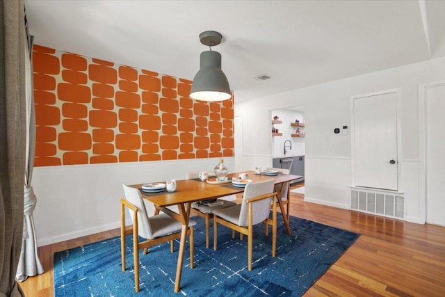 dining room with baseboards, visible vents, and wood finished floors