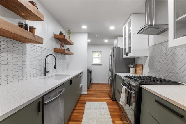 kitchen featuring open shelves, gas range oven, stainless steel dishwasher, a sink, and wall chimney range hood