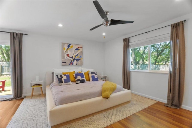 bedroom with recessed lighting, multiple windows, baseboards, and wood finished floors