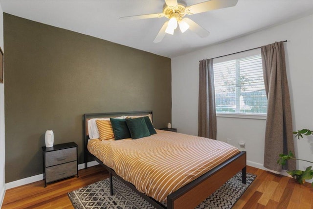 bedroom with ceiling fan, baseboards, and wood finished floors