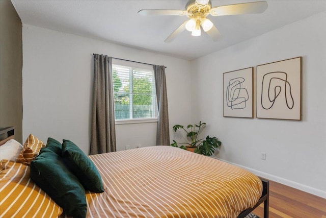 bedroom with ceiling fan, baseboards, and wood finished floors