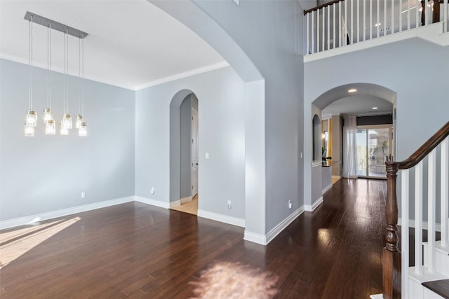 foyer featuring baseboards, stairway, ornamental molding, wood finished floors, and arched walkways