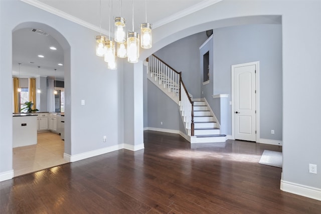 unfurnished room featuring arched walkways, visible vents, baseboards, and wood finished floors