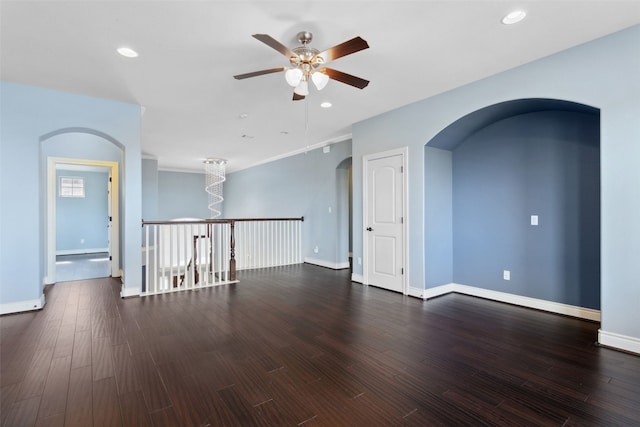 empty room featuring recessed lighting, wood finished floors, arched walkways, and baseboards