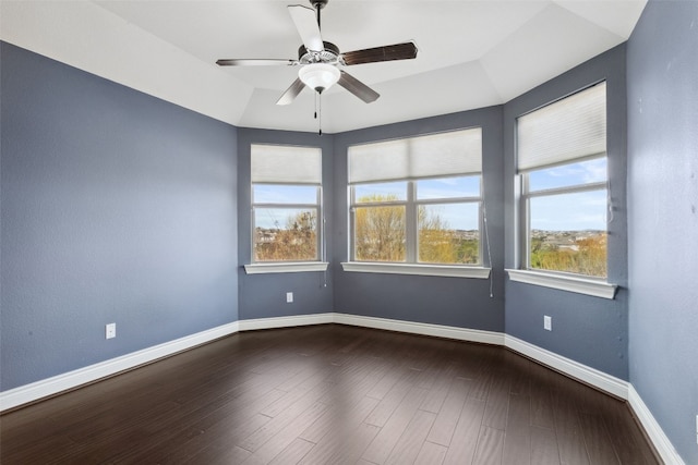 empty room featuring a ceiling fan, dark wood-style floors, and baseboards