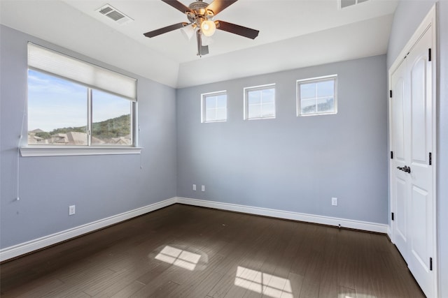 unfurnished bedroom featuring a ceiling fan, dark wood-style floors, visible vents, and baseboards