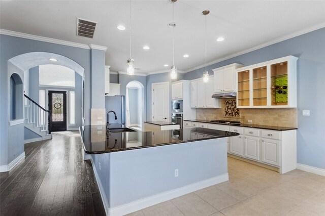 606 Anfield Cir, Austin, TX 78738 - kitchen with stainless steel appliances, arched walkways, under cabinet range hood, crown molding, and decorative backsplash