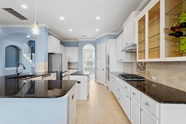 606 Anfield Cir, Austin, TX 78738 - kitchen with stainless steel appliances, under cabinet range hood, ornamental molding, a center island, and backsplash