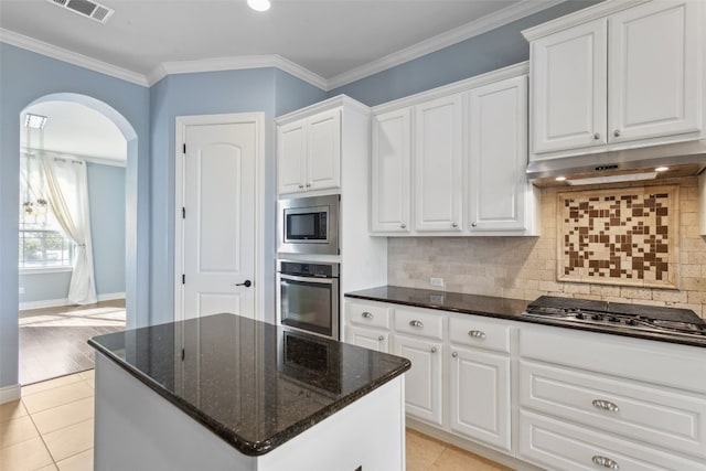 606 Anfield Cir, Austin, TX 78738 - kitchen featuring appliances with stainless steel finishes, arched walkways, white cabinets, dark stone countertops, and light tile patterned floors