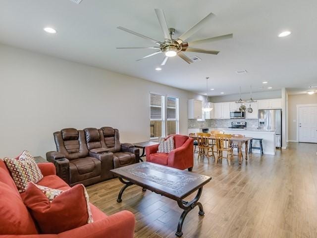 living room featuring light wood-style floors, ceiling fan, and recessed lighting