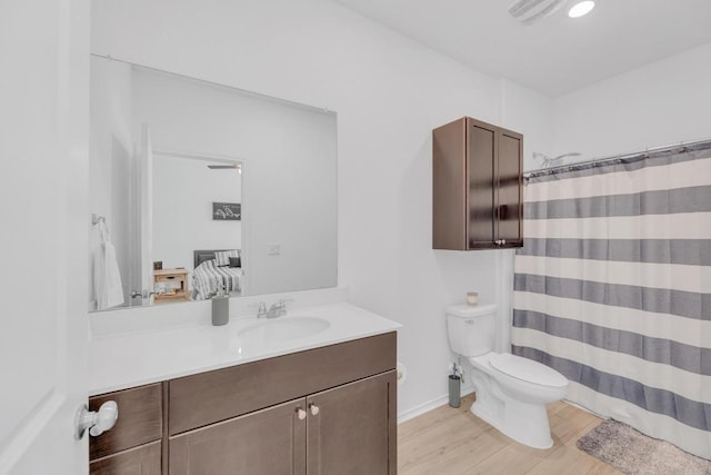 ensuite bathroom with ensuite bathroom, toilet, wood finished floors, vanity, and a shower with curtain