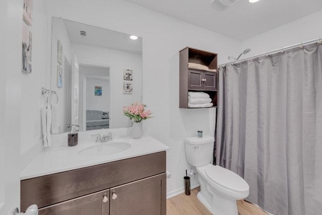 bathroom with toilet, a shower with shower curtain, wood finished floors, and vanity