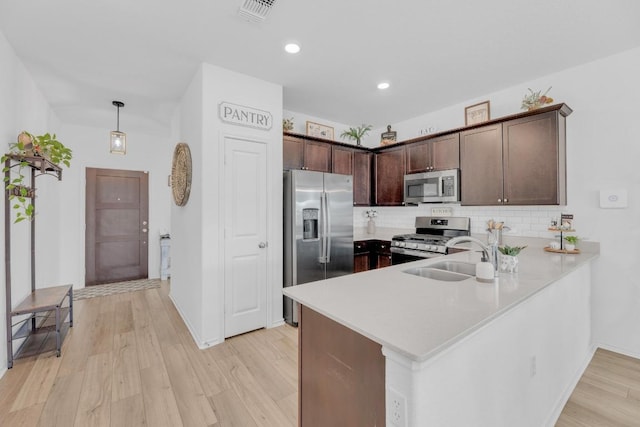 kitchen with stainless steel appliances, a sink, visible vents, light wood-style floors, and light countertops