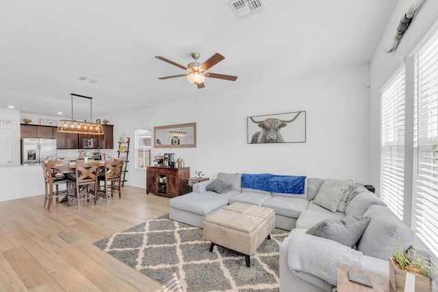 living area with light wood-type flooring, visible vents, and a ceiling fan