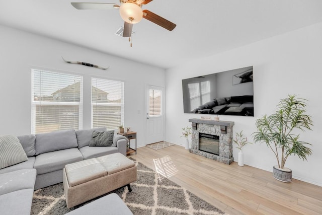 living room with baseboards, visible vents, a ceiling fan, wood finished floors, and a fireplace