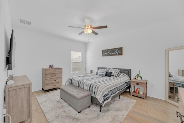 bedroom featuring light wood-style floors, baseboards, visible vents, and ceiling fan