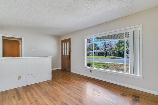 spare room with wood-type flooring, baseboards, and a textured ceiling