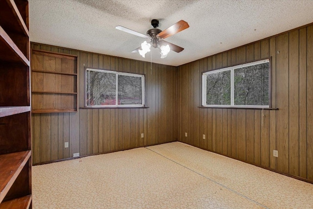 empty room with wood walls, a wealth of natural light, and a textured ceiling