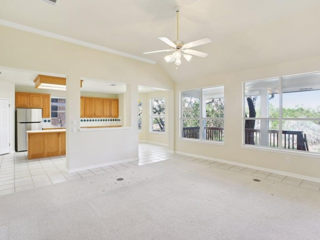 unfurnished living room with light tile patterned floors, lofted ceiling, light colored carpet, a ceiling fan, and baseboards