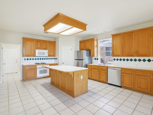 kitchen featuring light tile patterned flooring, stainless steel appliances, a kitchen island, a sink, and light countertops