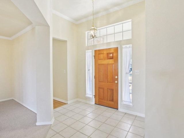 foyer featuring light tile patterned floors, baseboards, crown molding, and an inviting chandelier