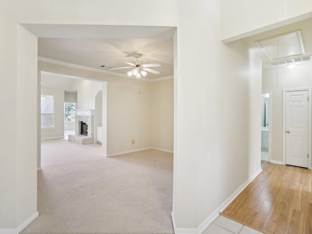 hallway with attic access, carpet flooring, crown molding, and baseboards