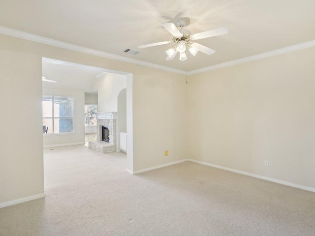 unfurnished room featuring ornamental molding, light colored carpet, visible vents, and a stone fireplace