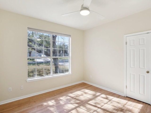 empty room featuring light wood-style floors, plenty of natural light, and baseboards