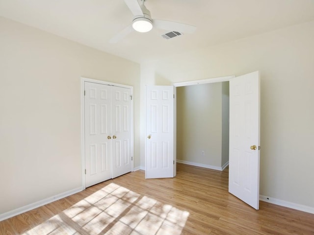 unfurnished bedroom featuring light wood finished floors, a closet, visible vents, a ceiling fan, and baseboards